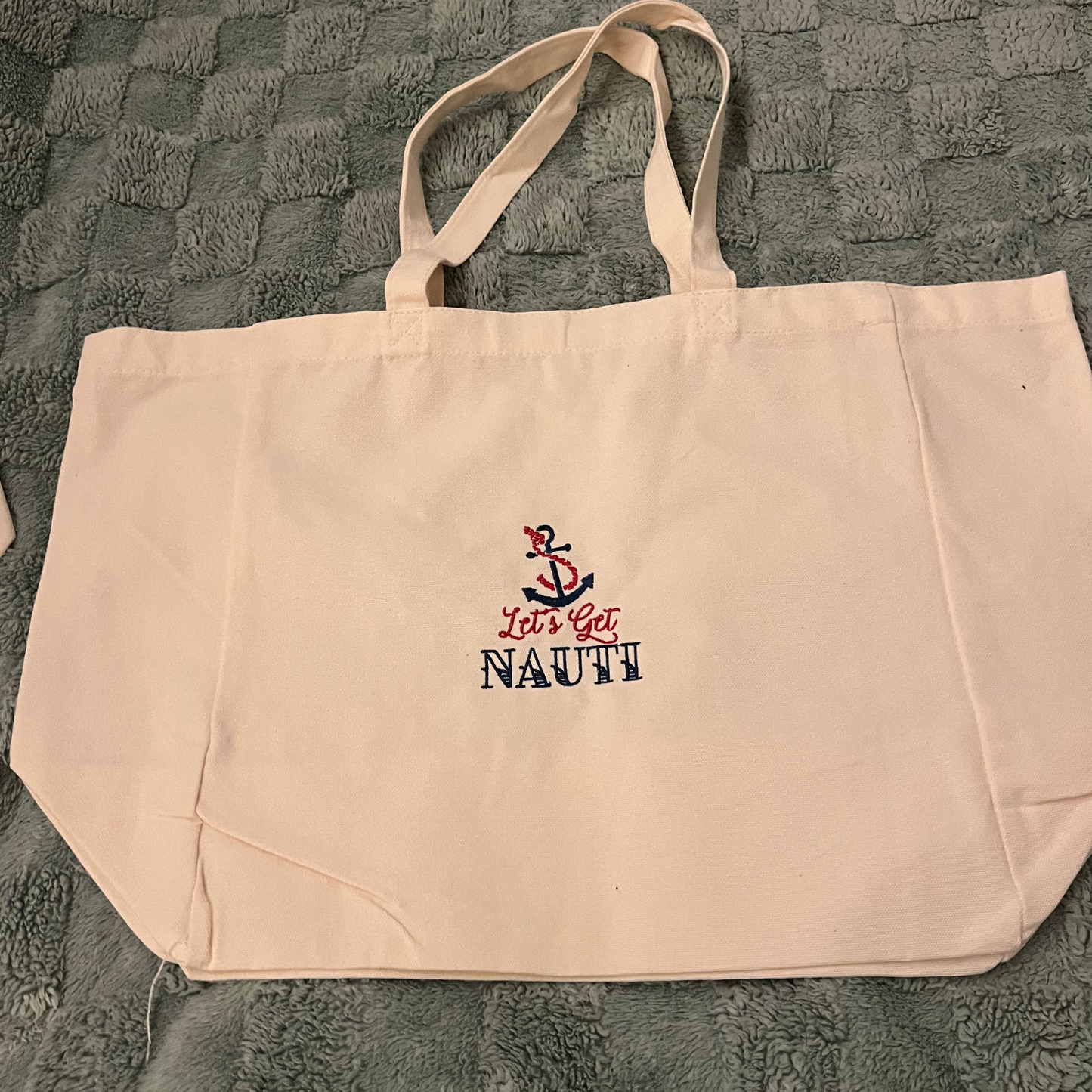 Reusable shopping bag with Let's get Nauti embroidered on it